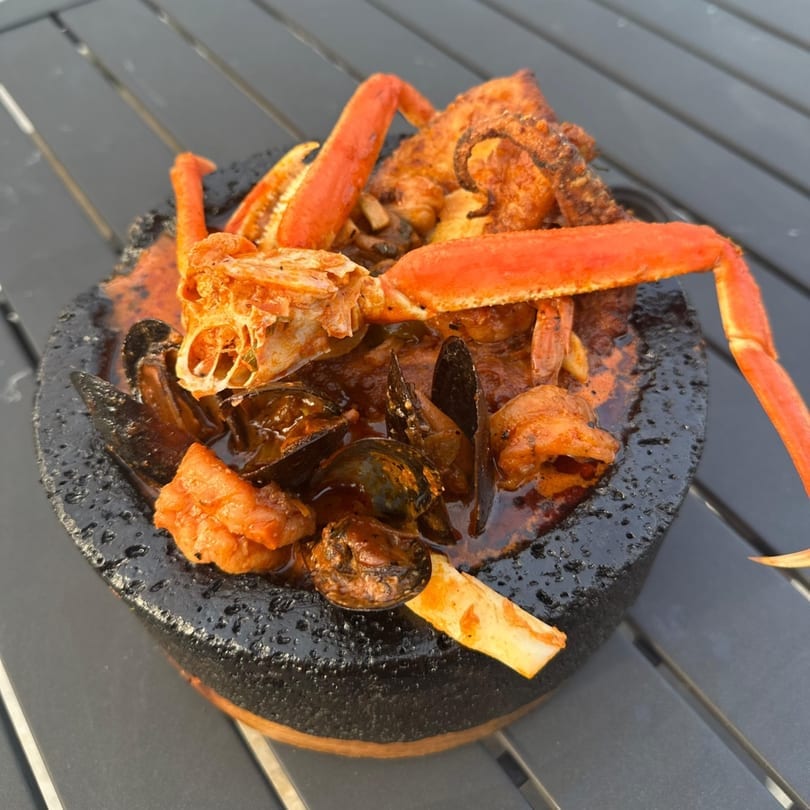 Seafood molcajete with crab legs, mussels, octopus, and shrimp in a rich red sauce.